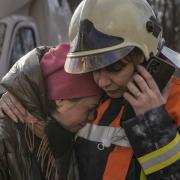 A firefighter comforts a woman outside a destroyed apartment building after a bombing in a residential area in Kyiv, Ukraine, Tuesday, March 15, 2022. Russia's offensive in Ukraine has edged closer to central Kyiv with a series of strikes hitting a