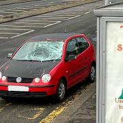 A red Volkswagen Polo with substantial damage was parked at a bus stop on the road after the incident